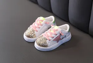 Detailed view of fashionable girls' white sneakers with pink stars and gold sequin toes