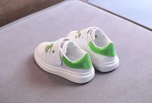 Dettaglio di sneakers in pelle bianca per bambini con tallone verde e chiusura in velcro