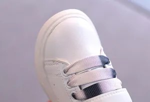 Dettaglio ravvicinato di sneaker in pelle bianca per bambini con lacci sfumati colorati