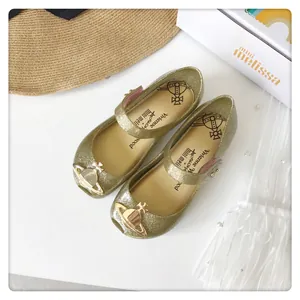 Vista superior de zapatos jelly dorados con purpurina y el icónico amuleto orb