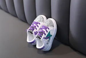 Detailed view of girl's white fashion sneakers with silver sequins and purple laces