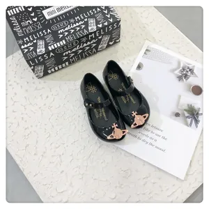 Vista detallada de zapatos de gelatina negros para niñas con logo de planeta oro rosa y caja.