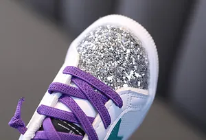 Macro shot of sparkling silver sequins and purple laces on a stylish girl's casual sneaker
