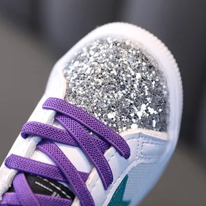 Close-up of stylish girls' casual sneakers featuring silver glitter toe and purple laces