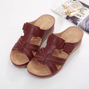 Detailed view of maroon wedge sandals with laser-cut hollow design and thick sole