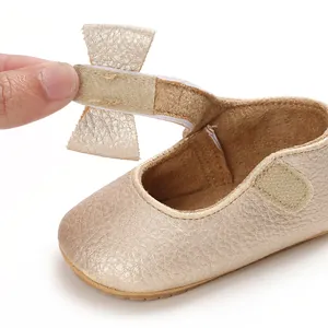 Detail shot of a golden baby princess walking shoe featuring a bow and velcro strap