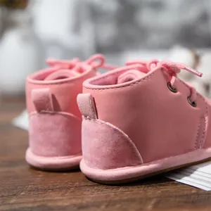 Detailed back view of pink suede-style baby boots with soft rubber soles and laces