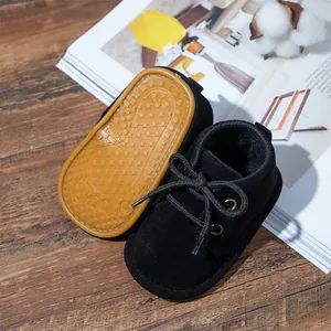 Close-up detail of black suede lace-up baby boots featuring a non-slip yellow rubber sole