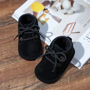 Close-up of black faux suede baby walking shoes featuring classic lace-up bow details