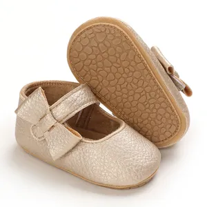 Detailed view of gold baby Mary Jane shoes with soft non-slip rubber soles and side bows