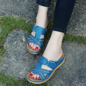 Close-up view of blue women's wedge sandals with hollow cross straps on natural stone ground