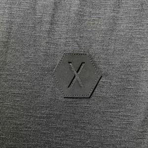 Vista detallada del tejido gris y del parche X hexagonal en una camiseta casual de hombre