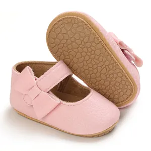 Close-up of pink baby girl princess shoes with soft rubber sole and bow detail.