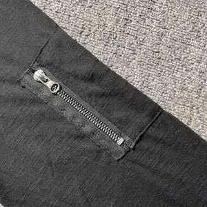 Primer plano del detalle de la cremallera en el brazo de una camiseta negra de manga larga