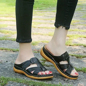 Close-up detail of women's black hollow cross wedge slippers worn on feet outdoors
