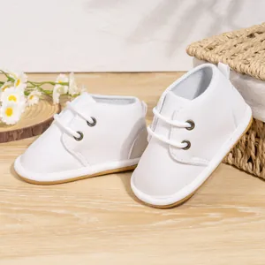 Close-up of white lace-up anti-slip baby walking shoes on wooden surface