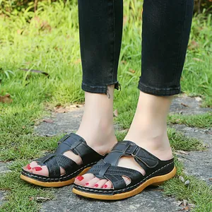 Close-up of women's black platform wedge sandals with hollow cross strap design outdoors.