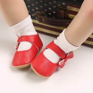 Detailed macro view of red soft leather baby princess walking shoes with a cute bow