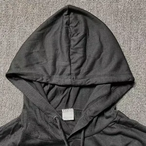 Vista de detalle macro de la camiseta negra de manga larga con capucha y etiqueta de cuello