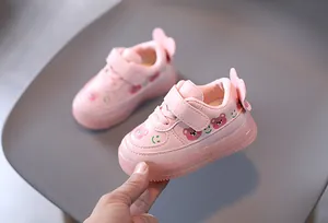 Detail showing pink toddler light-up sneakers with bear prints and soft soles.