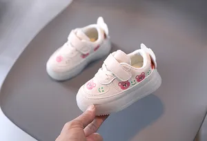 Detailed view of baby white sneakers featuring cute bear and smiley face cartoon patterns