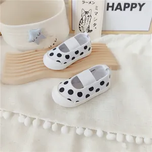 Vista detallada de zapatos de lona para bebé blancos con lunares negros y elástico.