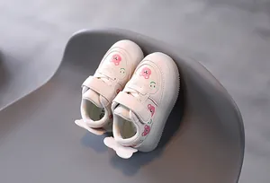Detailed view of stylish white toddler sneakers with cute pink bear and smiley patterns