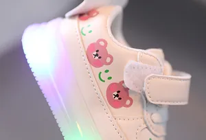 Close-up detail of toddler LED sneakers featuring cute bear and smiley face patterns