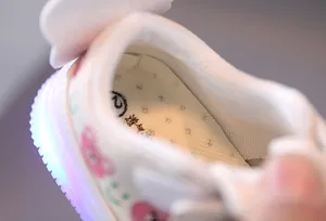 Detailed view of breathable insole and blue LED light-up sole of white kids' shoes