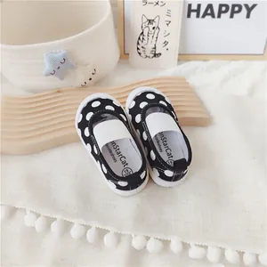 Detalle de zapatos de lona Mary Jane para bebé con lunares blancos y negros y elástico