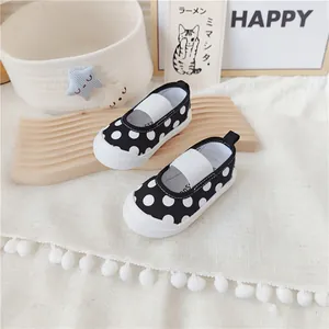 Detalle de zapatos de lona negros con lunares para niñas con suelas muy blandas