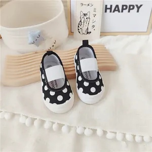 Vista detallada de zapatos de lona para bebés con lunares blancos y negros y elástico