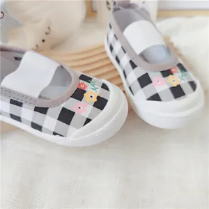 Primer plano detallado de zapatos de lona a cuadros para niña con bordado floral