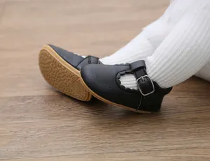 Close-up of black baby Mary Jane walking shoes with scalloped trim on wooden floor