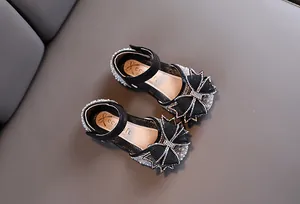 Détail de chaussures de princesse noires pour filles avec nœud en strass et perles