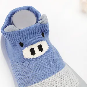 Close-up of breathable blue knitted baby walker shoes with cute cartoon pig design