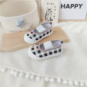 Vista detallada de zapatos de lona de cuadros para bebé niña con bordado floral.