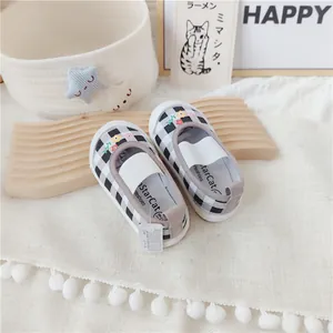 Primer plano de zapatos de lona a cuadros para niña con bordado floral y suela blanda