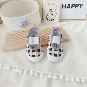 Detalle de zapatos de lona a cuadros para niña con bordado floral y elástico.