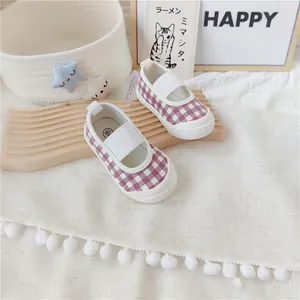 Primer plano de zapatos de lona para niñas a cuadros morados con correa elástica