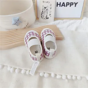 Detalle de zapatos de lona a cuadros morados para bebé con elástico en fondo blanco