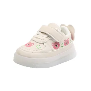 Cute toddler light-up sneakers with bear and smiley patterns on cream soft sole