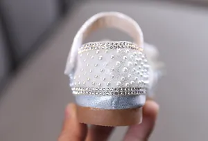 Gros plan des perles et strass sur le talon d'une chaussure de princesse argentée