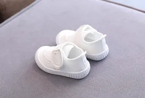 Detailed view of white infant walking shoes featuring breathable mesh and soft soles