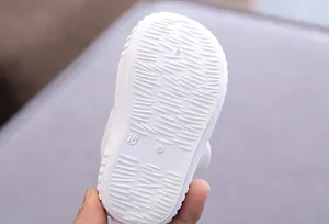 Close-up view of a white baby shoe sole showing anti-slip texture and size 16 mark