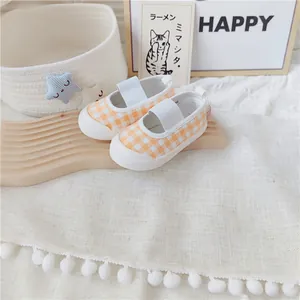Detalle de zapatos de lona para bebé niña con cuadros naranjas y correa elástica