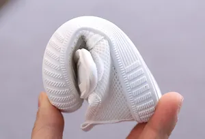 Detail showing a soft white mesh baby walking shoe being bent to demonstrate flexibility.