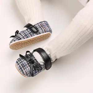 Detailansicht von Baby-Mädchen Tweed Mary Janes mit schwarzer Schleife und Gummisohle.