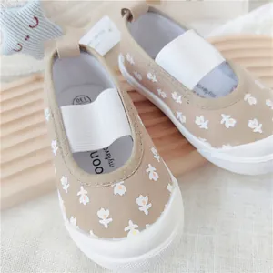 Primer plano de zapatos de lona con flores caqui para niñas con correa elástica suave.
