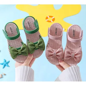 Detailed view of girls' summer sandals featuring large sparkling bows and woven-texture soles.
